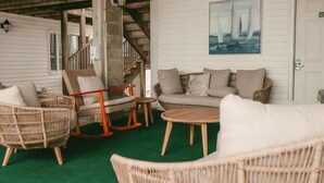 A cozy indoor seating area with wicker furniture, a green carpet, and a painting of sailboats on the wall. - Atlantic Motel (Hampton)