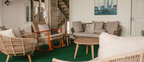 A cozy indoor seating area with wicker furniture, a green carpet, and a painting of sailboats on the wall.