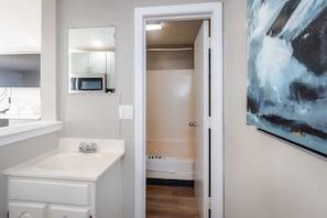 A bathroom with a sink, mirror, and a shower area.