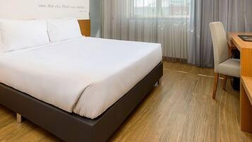A hotel room with a bed, a desk, and a chair.
