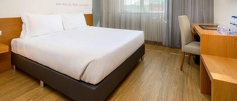 A hotel room with a bed, a desk, and a chair.