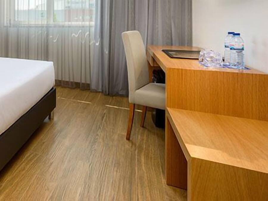 A hotel room with a bed, a desk, and a chair.