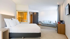 Una habitación de hotel moderna con una cama grande, un sofá, un escritorio y un televisor.
