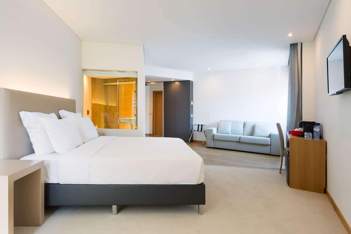 Une chambre d’hôtel moderne équipée d’un grand lit, d’un canapé, d’un bureau et d’une télévision.
