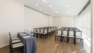 Un salón de conferencias con una larga mesa, sillas y un ventanal.