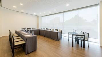 Uma sala de conferências com uma mesa comprida, cadeiras e uma janela grande.