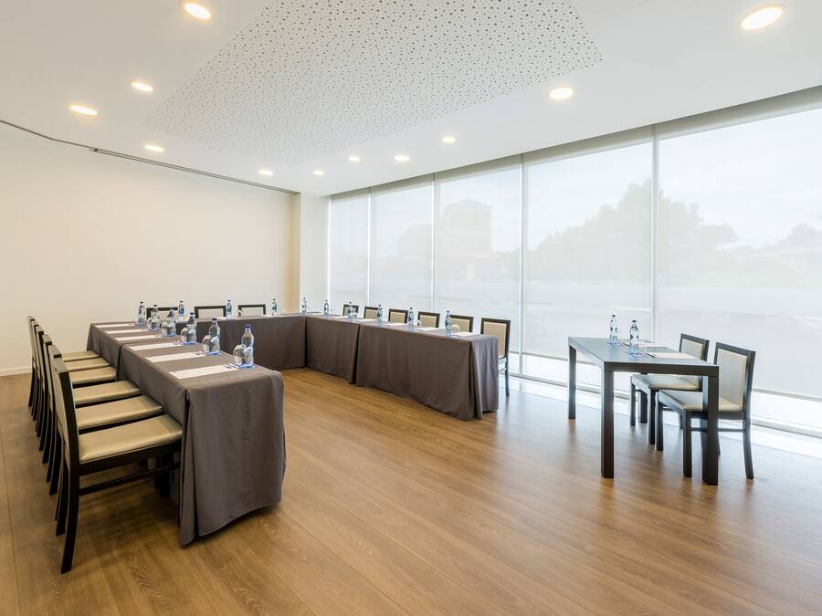 Uma sala de conferências com uma mesa comprida, cadeiras e uma janela grande.
