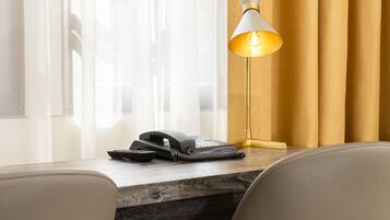 A hotel room with a desk, two chairs, a telephone, and a lamp.