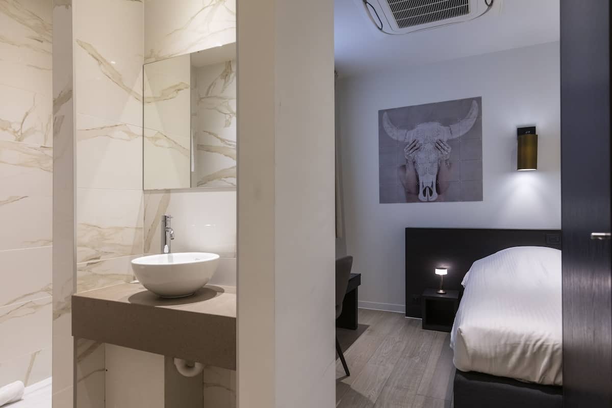 Un baño moderno con pared de mármol, un lavamanos blanco y un espejo.