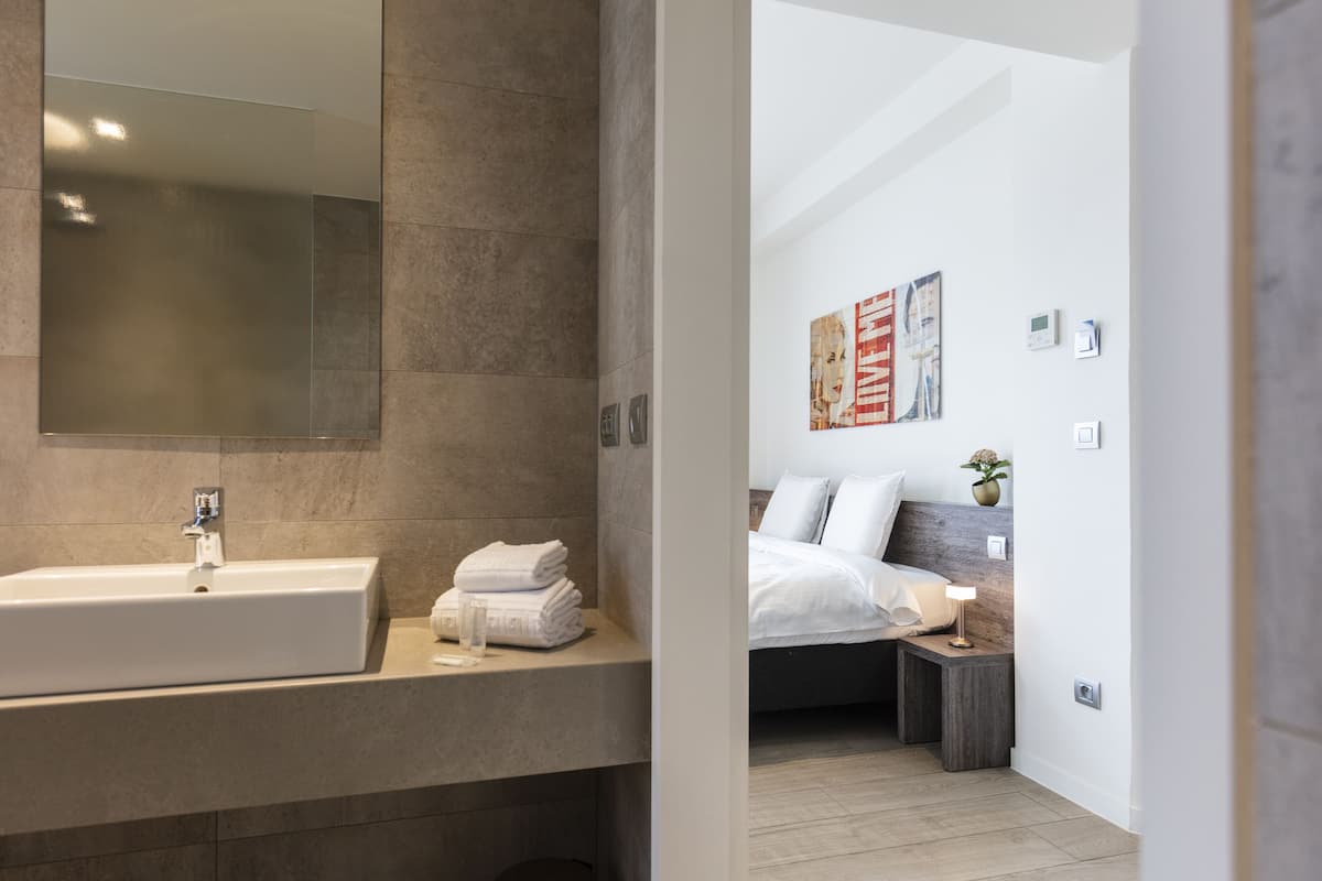 Un baño moderno con un espejo grande, un lavamanos y una pila de toallas ordenadas.