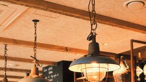 A bar with hanging lamps, shelves stocked with bottles, and a chalkboard menu. - The Market by Parkhotel (Kortrijk)