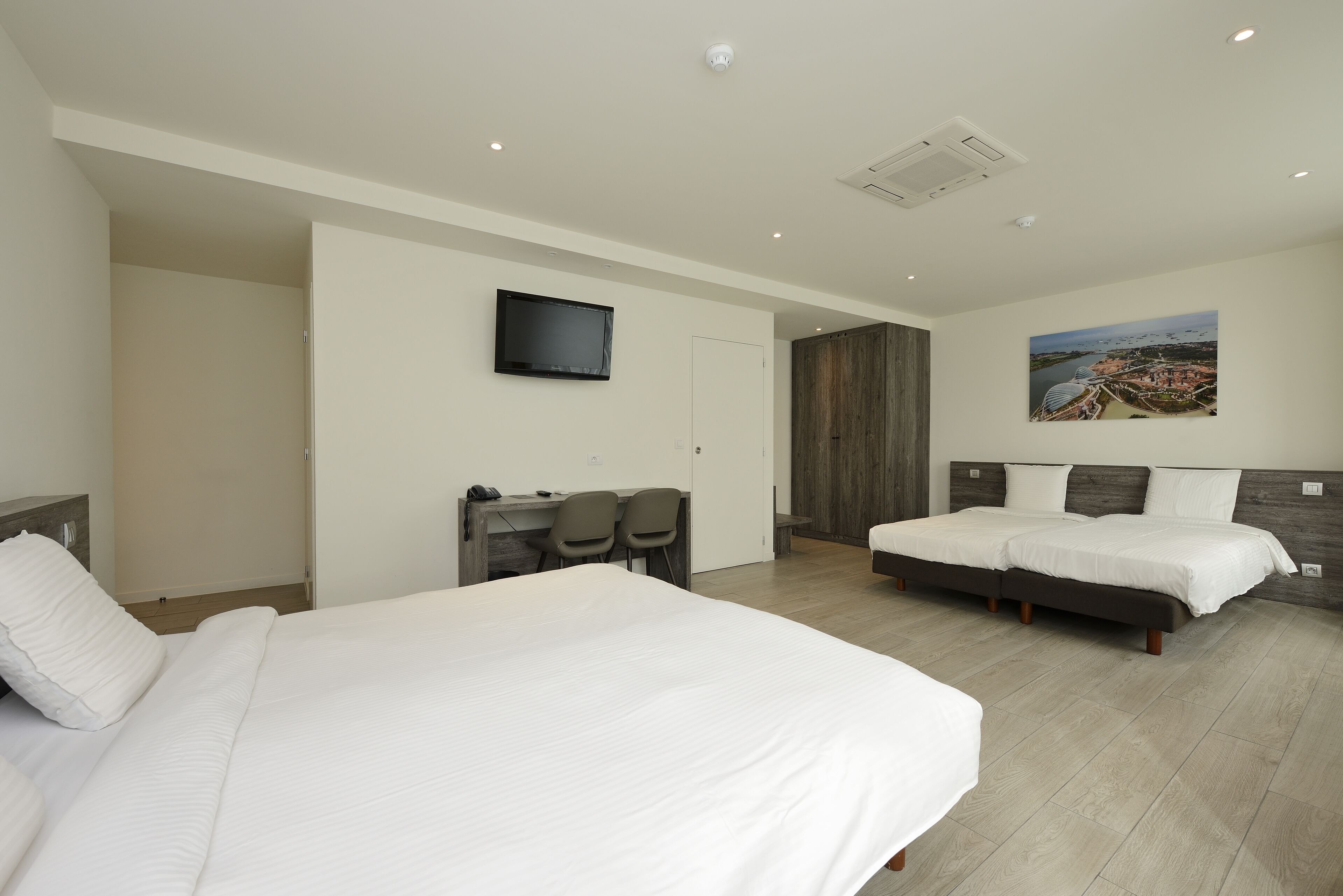 Una habitación de hotel moderna con una cama grande, un escritorio con sillas, un televisor y un cuadro en la pared.