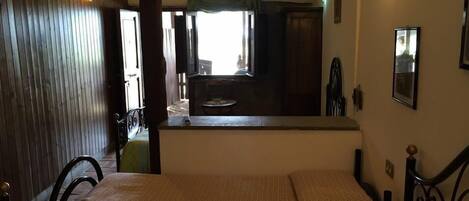 Una habitación con dos camas, una puerta de madera, una mesita y vistas a una ventana y una puerta que da al exterior.