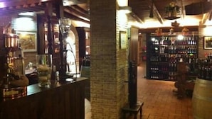 A bar area with wooden beams, brick walls, and shelves of liquor bottles. - Agriturismo Monte Due Torri (Genzano di Roma)