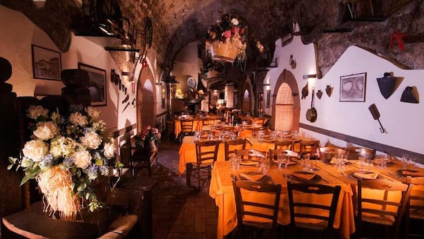 A restaurant with tables set for dining, a large floral arrangement, and rustic decor. - Agriturismo Monte Due Torri (Genzano di Roma)
