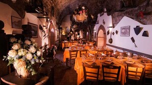 A restaurant with tables set for dining, a large floral arrangement, and rustic decor. - Agriturismo Monte Due Torri (Genzano di Roma)