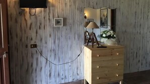 A room with a wooden paneled wall, a flat-screen TV mounted above a wooden dresser, and a mirror above the dresser. - Agriturismo Monte Due Torri (Genzano di Roma)