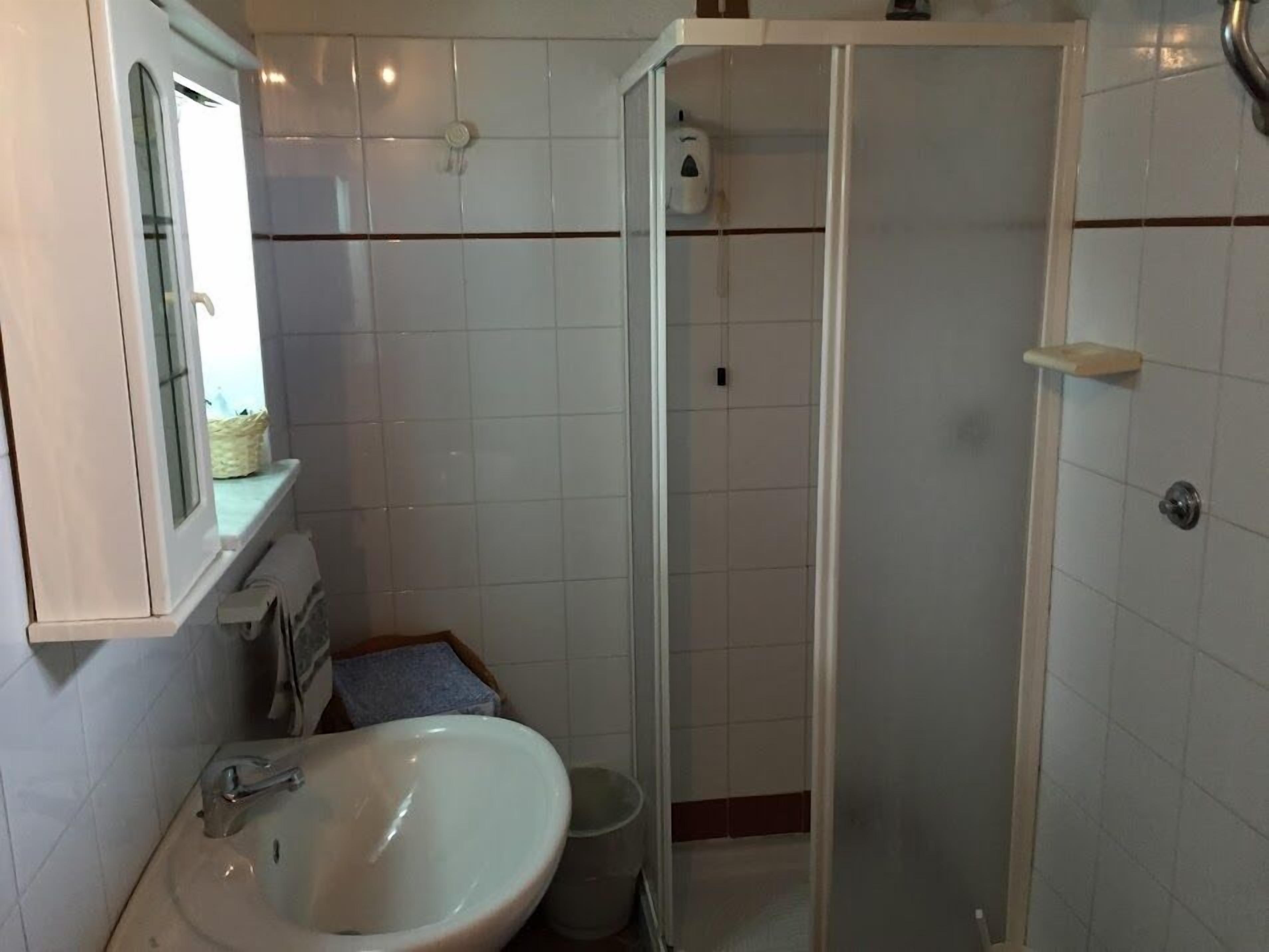A bathroom with a sink, mirror, and shower.