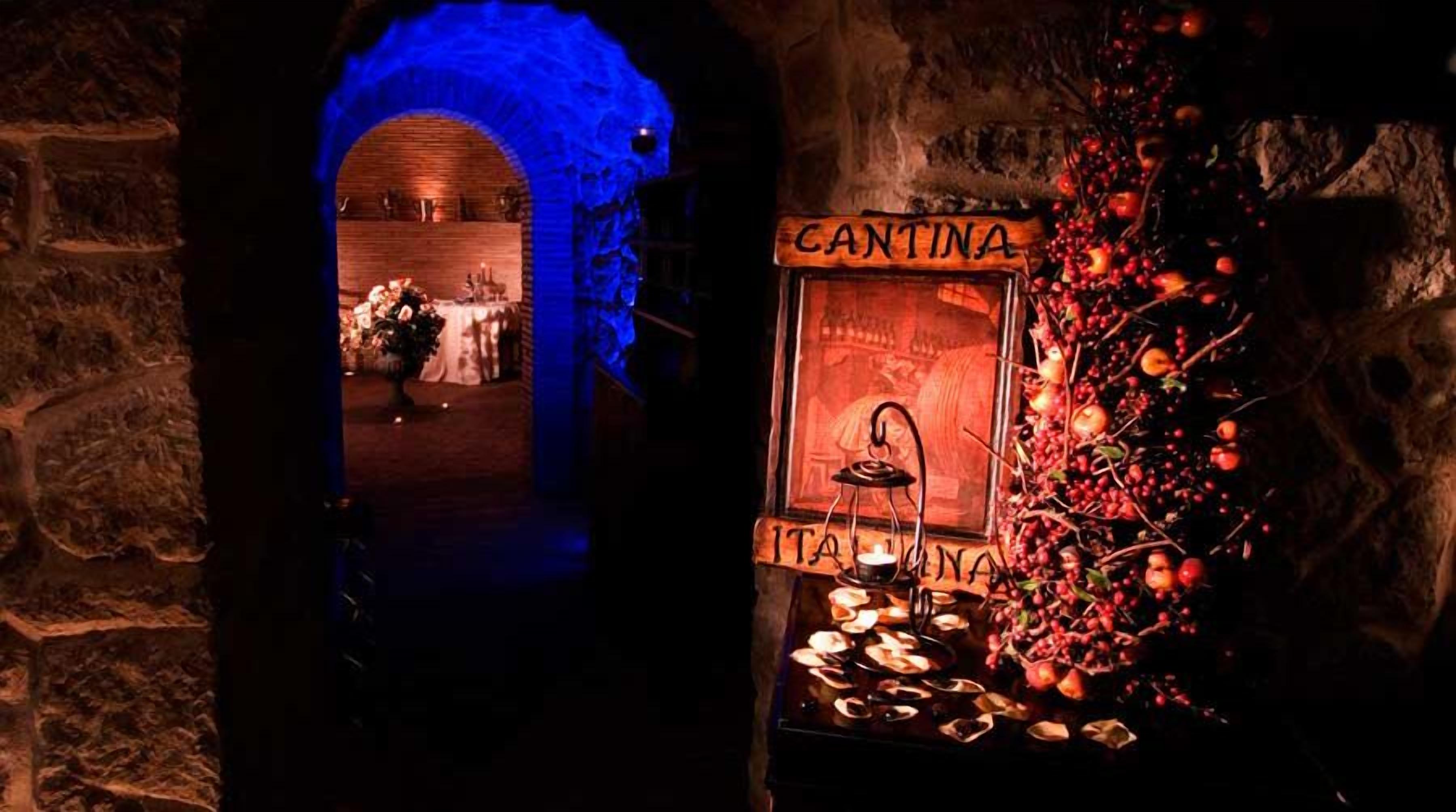 An archway leading to a room with a sign reading "CANTINA ITALIANA" and a display of fruits and candles.
