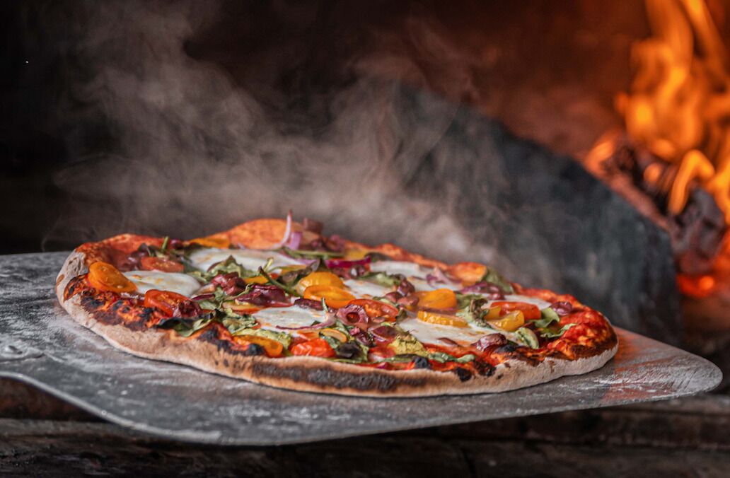 Una pizza sobre una tabla de madera con un fondo rústico.