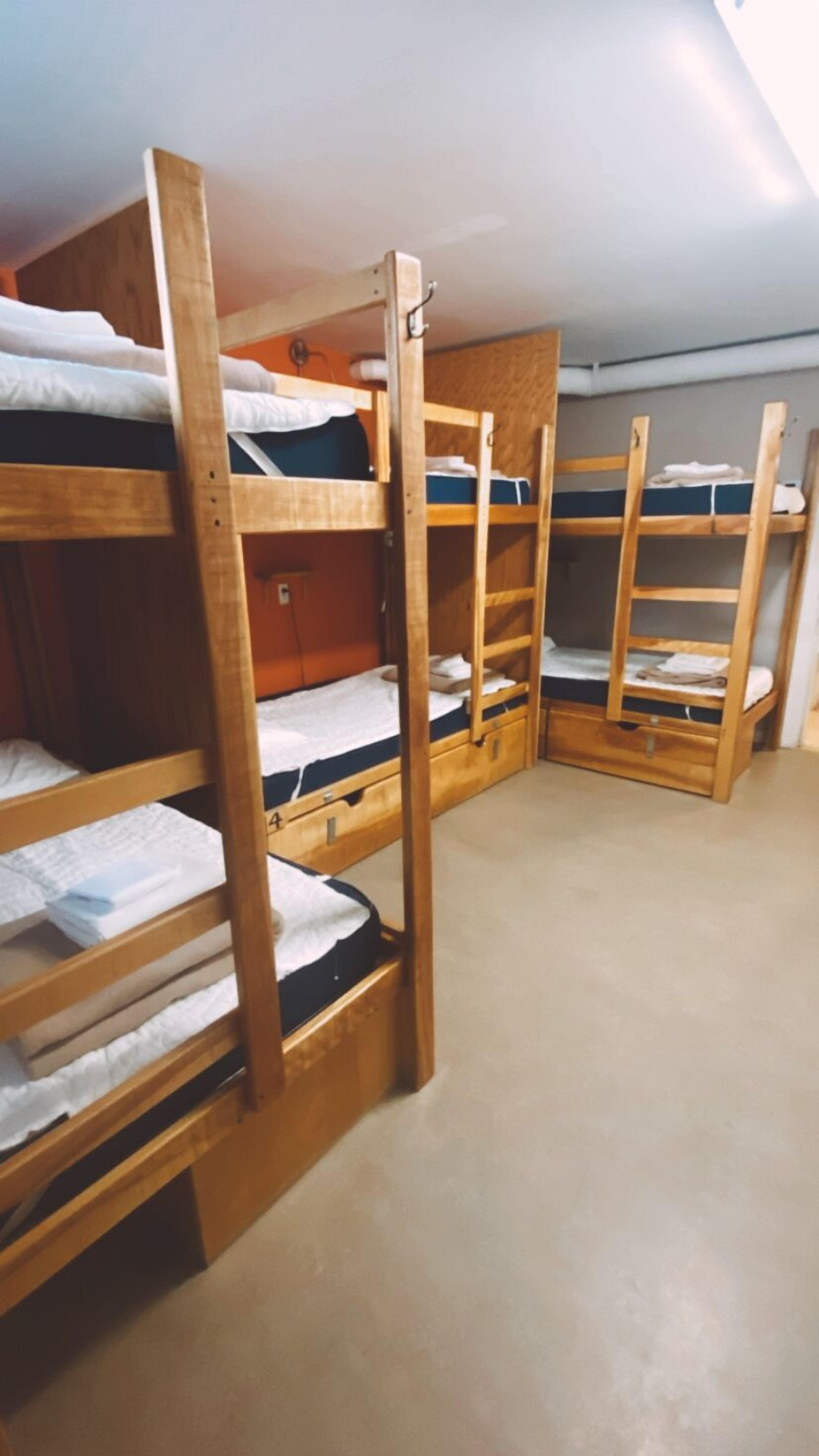 Een kamer met een slaapgedeelte met stapelbedden, houten wanden en een vloerbedekking.