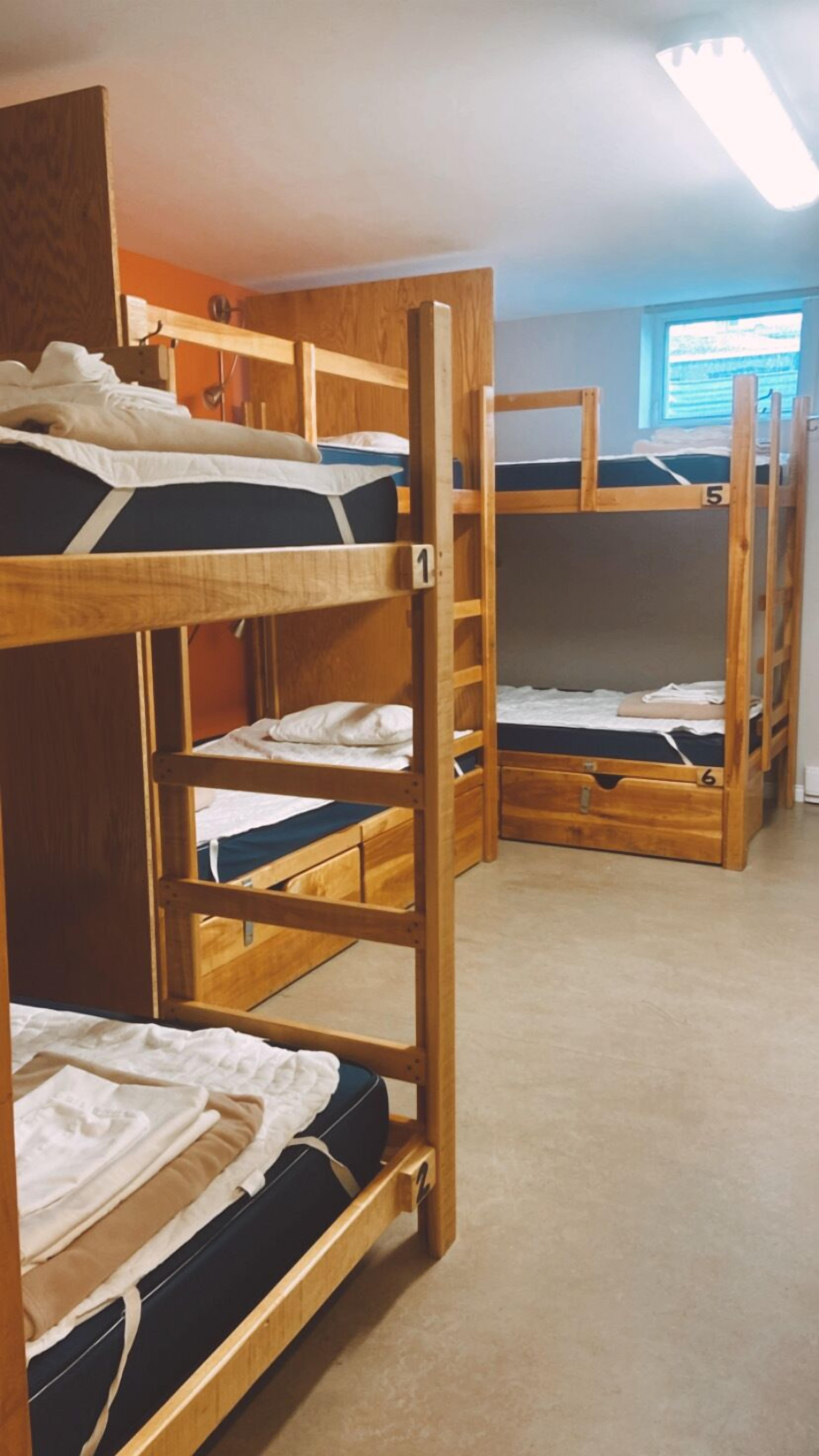 A dormitory room with bunk beds, numbered from 1 to 6, and a window providing natural light.