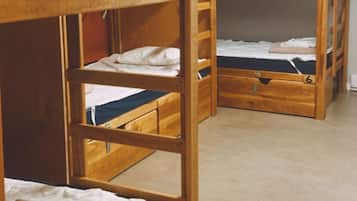 A dormitory room with bunk beds, numbered from 1 to 6, and a window providing natural light.