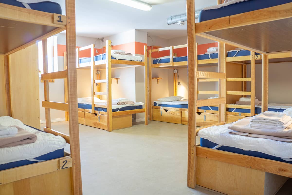 Un dormitorio con literas, cada una con un número. Hay cajones debajo de las camas y una lámpara en el techo.