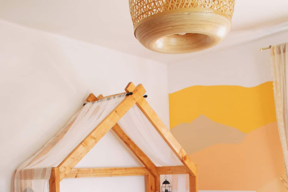 Una cama de madera con dosel, una mesita de noche y un mural en la pared.