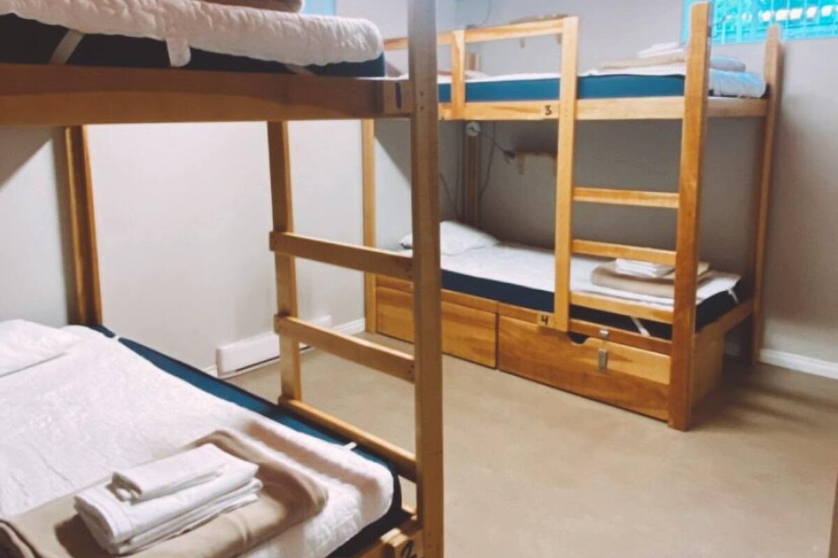 Camas literas en una habitación con suelo de madera y una ventana.