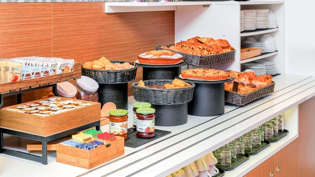 A buffet setup with various food items, including pastries, fruits, and condiments. - B&B Hotel Milano San Siro (Milan)
