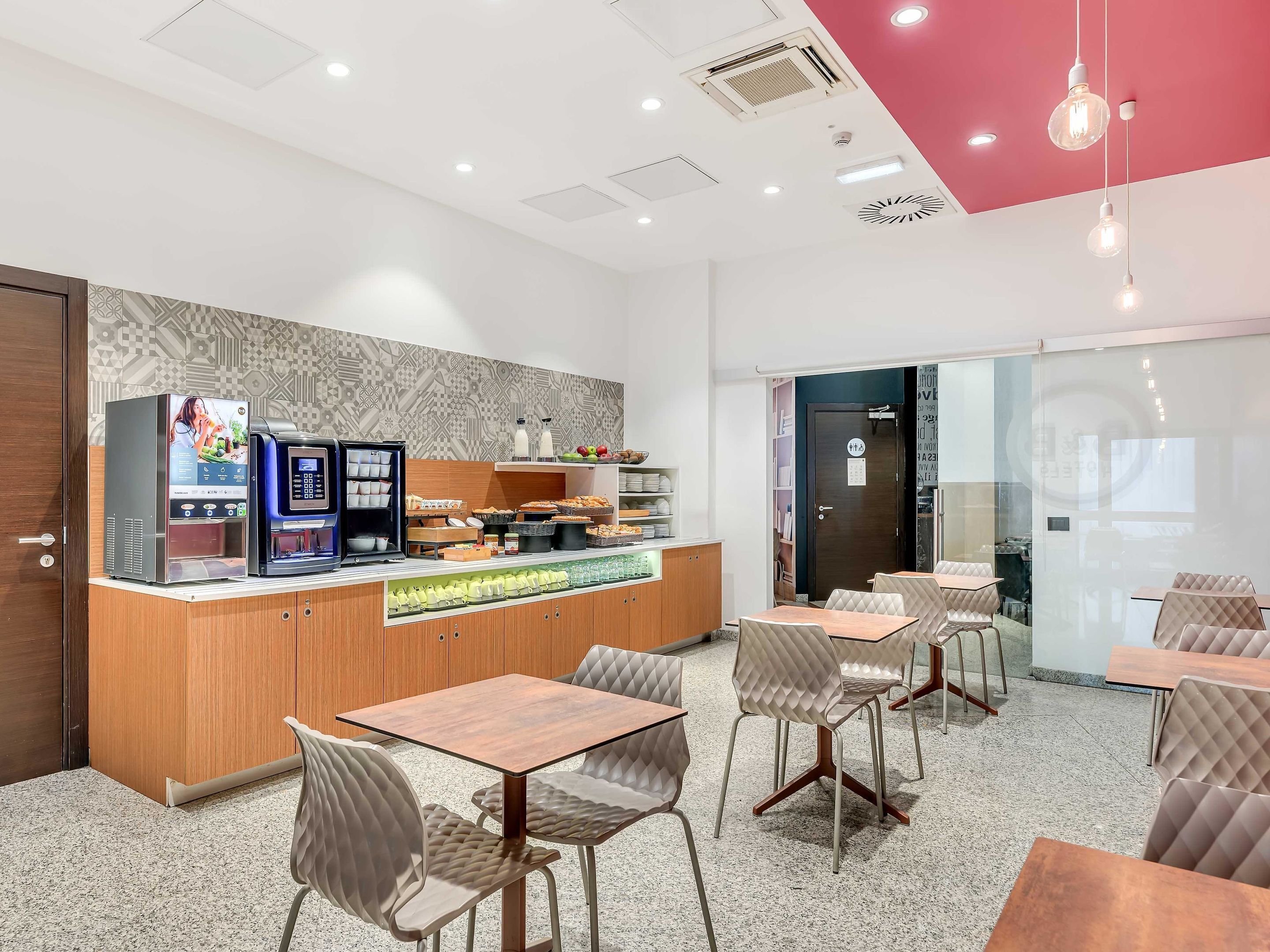 Un café moderno con mostrador, zona de estar y pared con diseño.