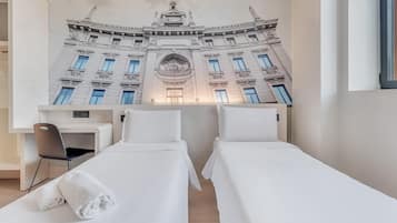 Una camera d'albergo con due letti, una scrivania e una sedia.