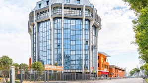 A modern hotel with a glass facade, a prominent rooftop sign, and a gated entrance. - B&B Hotel Milano San Siro (Milan)