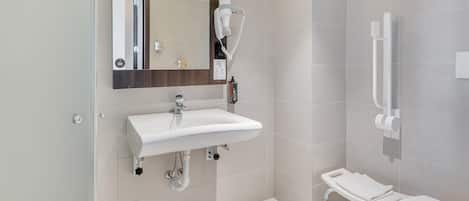 A modern bathroom with a white sink, mirror, and toilet.