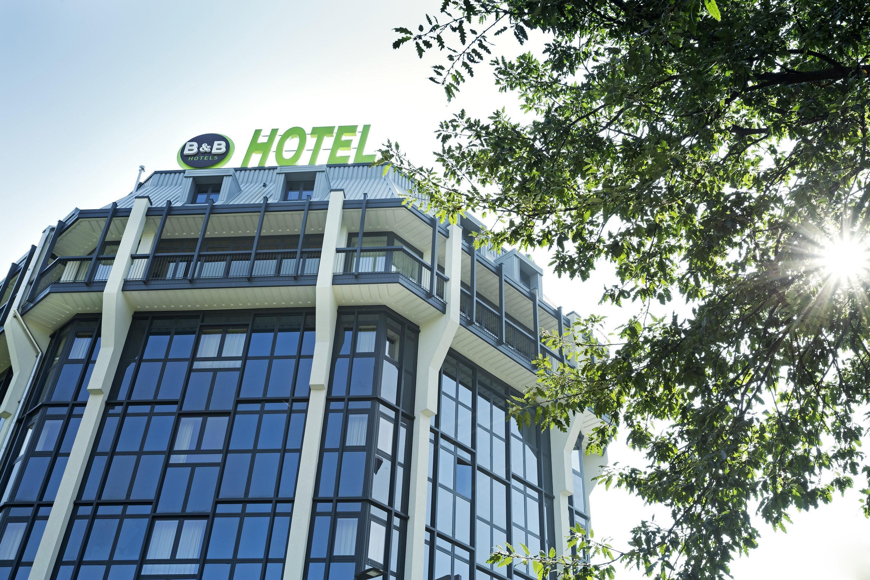 Ein modernes Hotelgebäude mit einer auffälligen Schild mit der Aufschrift "B&B HOTEL" und großen Fenstern.