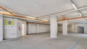 A spacious, empty parking garage with concrete floors and white walls, featuring a reception area and emergency equipment. - B&B Hotel Milano San Siro (Milan)