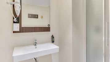 Un bagno con un lavandino bianco, un asciugacapelli montato a parete e uno specchio sopra il lavandino.
