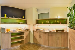 Una cocina moderna con armarios de madera, encimera verde y diversos utensilios de cocina.