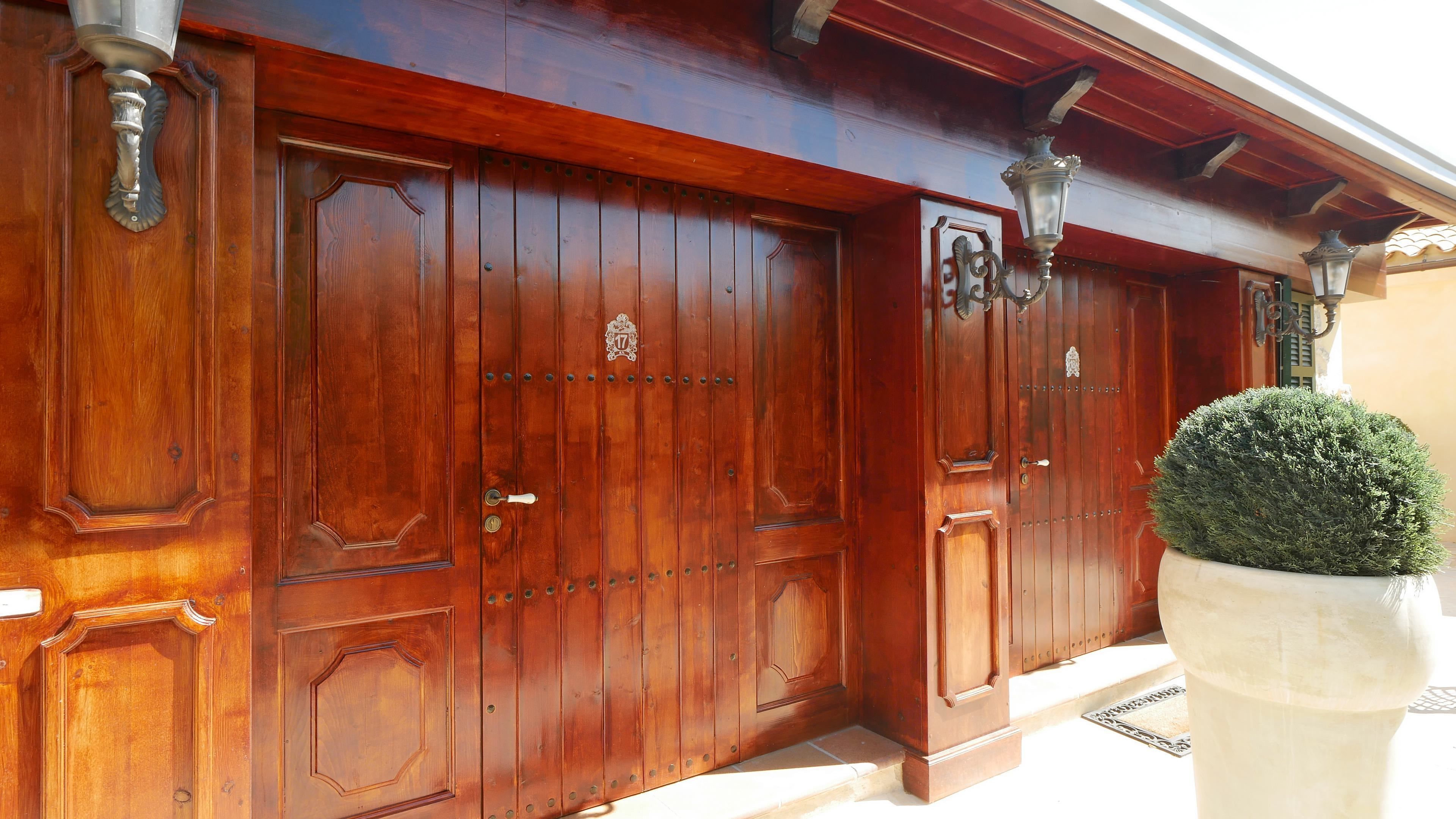 A large wooden double door with a brass handle and a brass number plate.