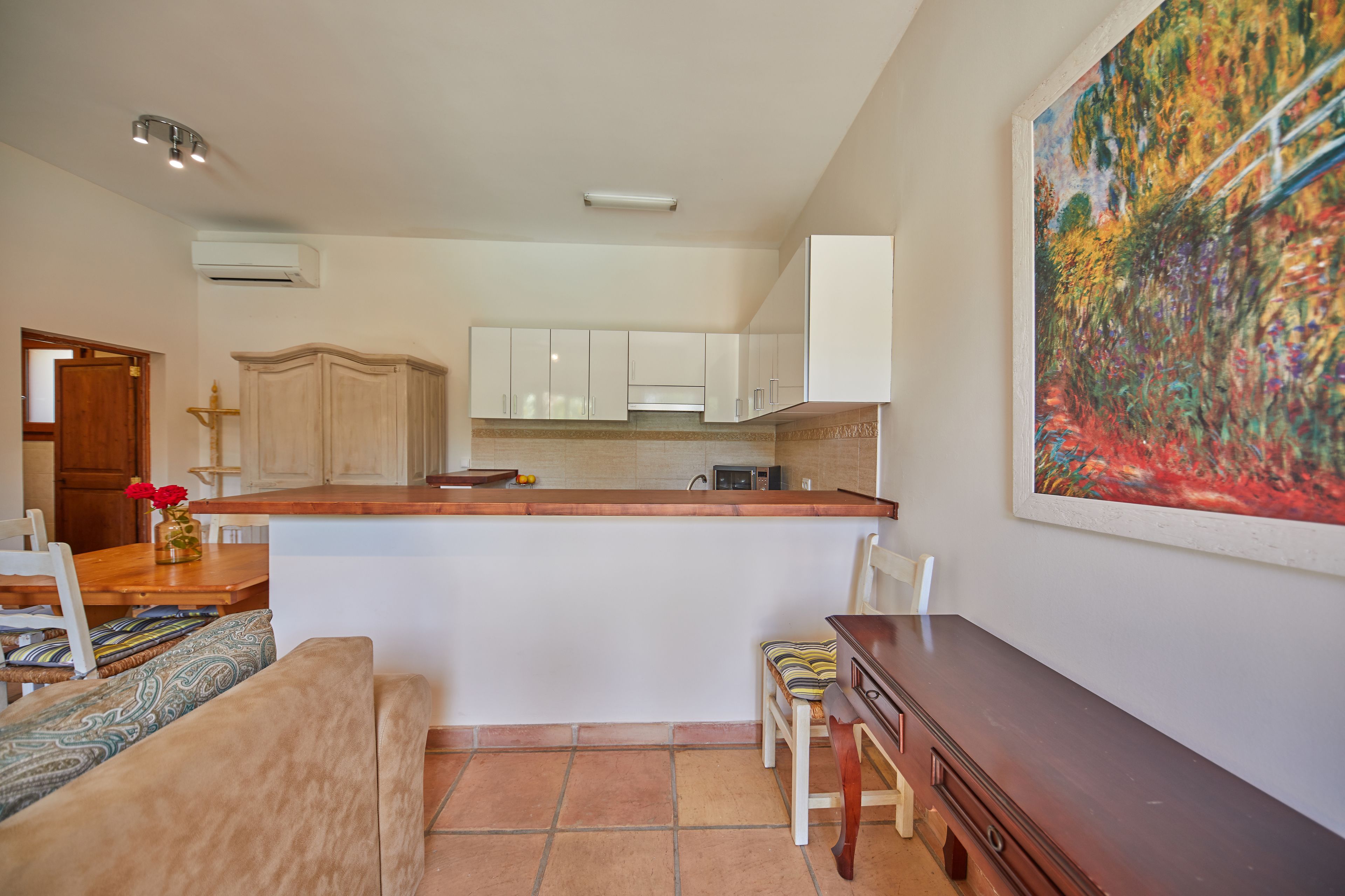 Una cocina moderna con armarios blancos, encimera de madera y una zona de comedor con banco y sillas.