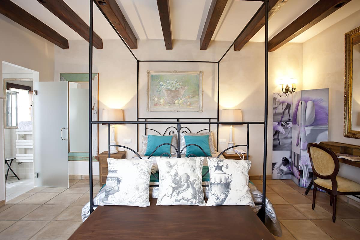 A bedroom with a wooden bed, a metal headboard, and a painting above the bed.