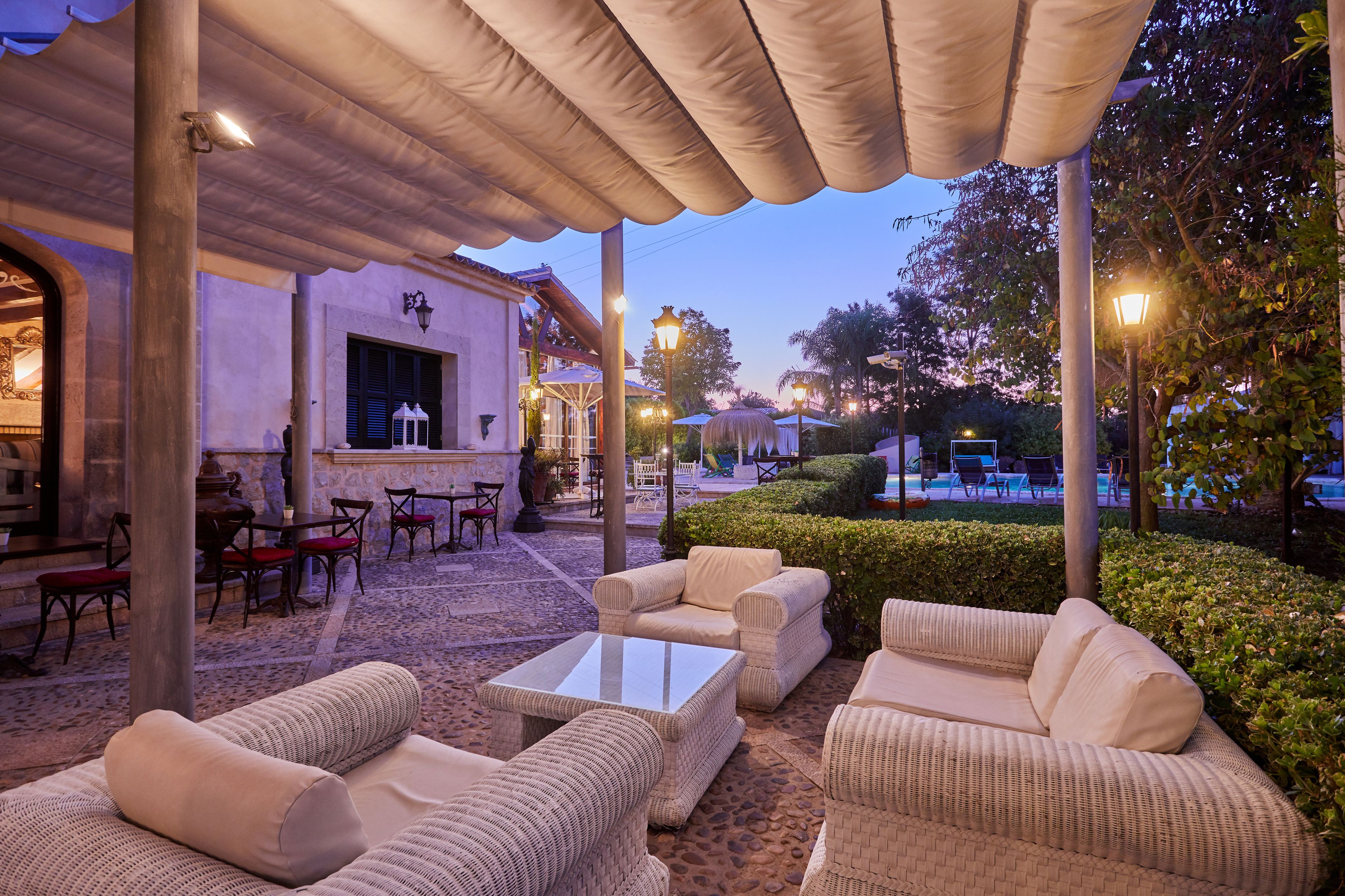 An outdoor patio area with wicker furniture, a bar, and a pool in the background.