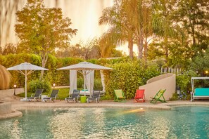 Una piscina al aire libre, sombrillas, sillones reclinables de piscina