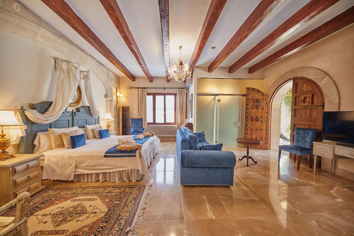 A spacious bedroom with a large bed, a blue sofa, and a television.