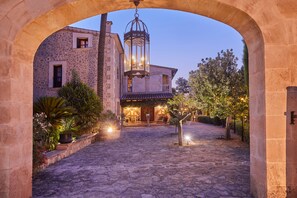 An outdoor courtyard with stone flooring, a building with a balcony, and a hanging lantern. - Sa Vinya des Convent Agroturismo (Inca)