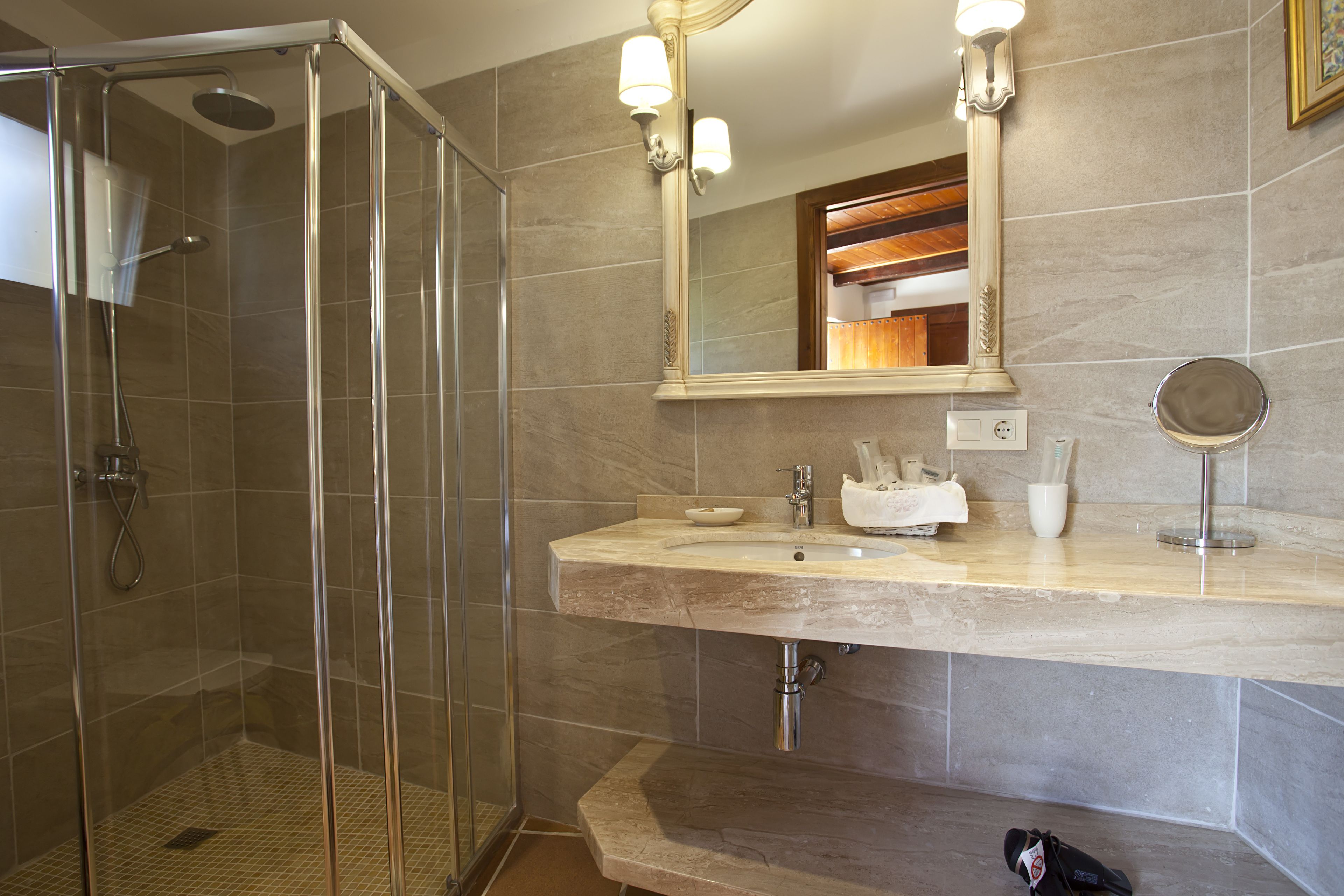A bathroom with a glass-enclosed shower, a sink with a mirror, and a towel rack.