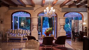 A spacious lobby with a chandelier, seating area, and large windows offering a view of a garden. - Sa Vinya des Convent Agroturismo (Inca)