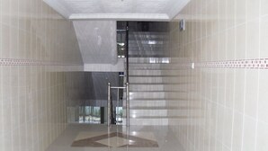 A modern elevator shaft with a glass door, surrounded by tiled walls. - Senator Hotel (Kumasi)