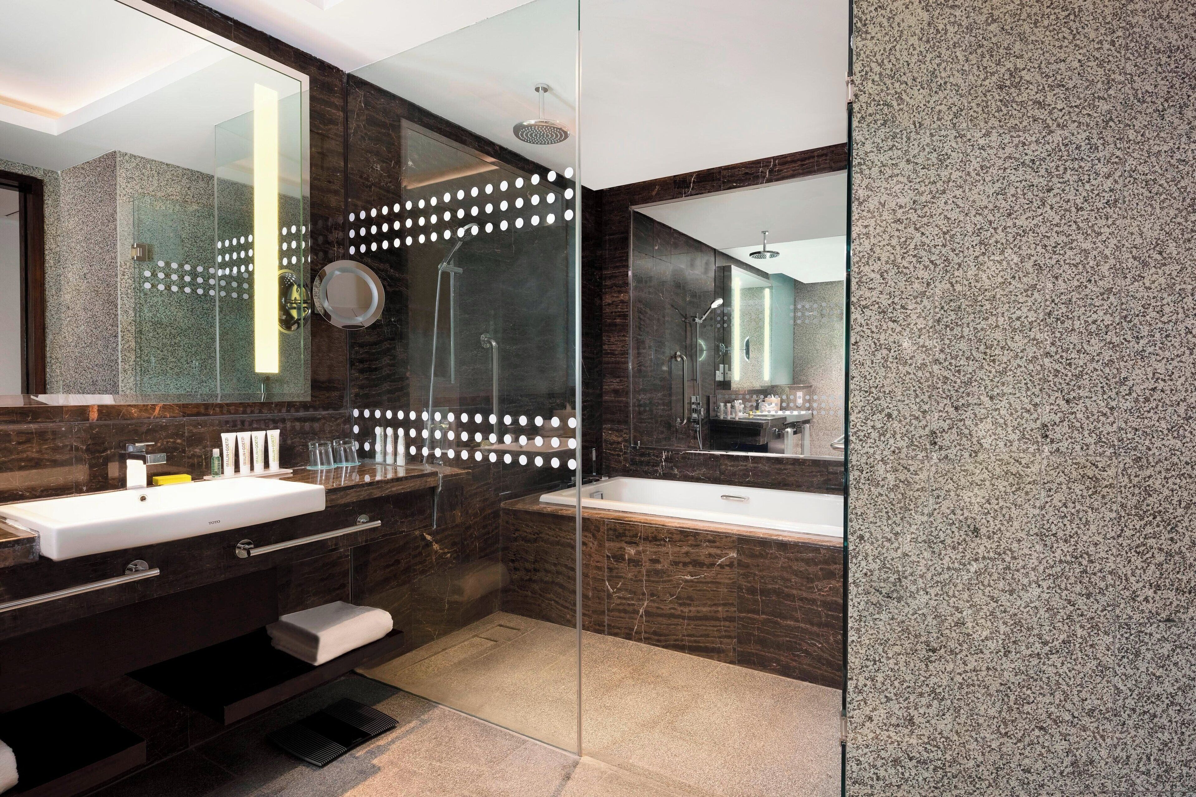 A modern bathroom with a glass-enclosed shower, a large mirror, and a vanity with a sink and countertop.